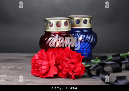 Memory lantern with candles, red carnations and ribbon on wooden table on grey background Stock Photo