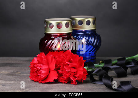 Memory lantern with candles, red carnations and ribbon on wooden table on grey background Stock Photo