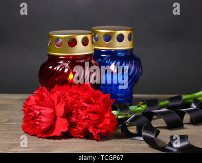 Memory lantern with candles, red carnations and ribbon on wooden table on grey background Stock Photo