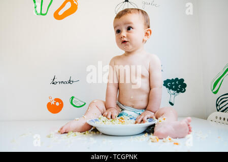 Baby eating by himself learning through the Baby-led Weaning method, exploring the flavors of food with curiosity. Stock Photo