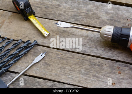Power drill tape measure with many drill bits on an old wood deck. Stock Photo