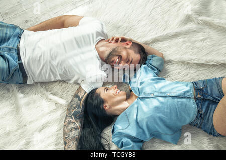 Top view of a beautiful couple laying over white background. girl with long dark hair. they are in love. Stock Photo