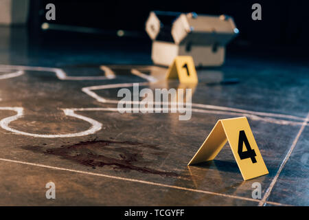 chalk outline, blood stain, investigation kit and evidence markers at crime scene Stock Photo