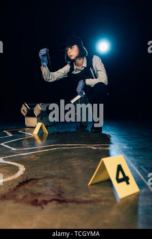 investigator holding knife and ziploc bag at crime scene Stock Photo