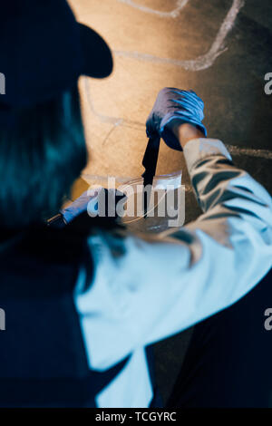 selective focus of investigator putting knife in ziploc bag at crime scene Stock Photo