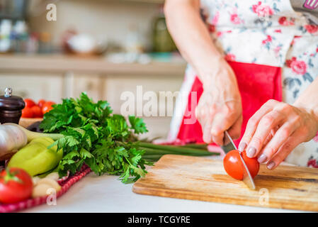 Female hand with knife slices bell pepper in kitchen. Cooking vegetables Stock Photo