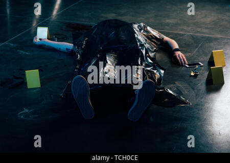 covered corpse near evidences on floor at crime scene Stock Photo