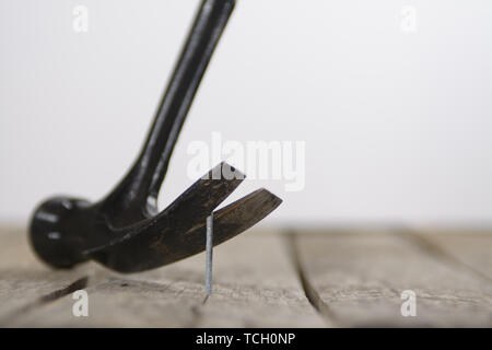 Hammer prying out a nail from a wood plank. Stock Photo