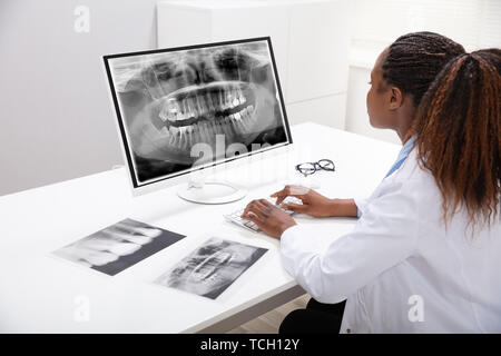 Female Doctor Looking At Teeth X-ray On Computer Over Desk In Clinic Stock Photo