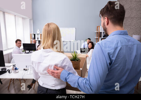 Smiling Young Manager Welcoming New Female Employee Introducing Her To Old Colleagues At Workplace Stock Photo