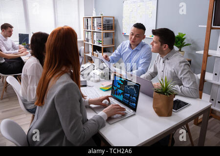 Businessman And Businesswoman Discussing Together In A Meeting While Using Laptop Stock Photo