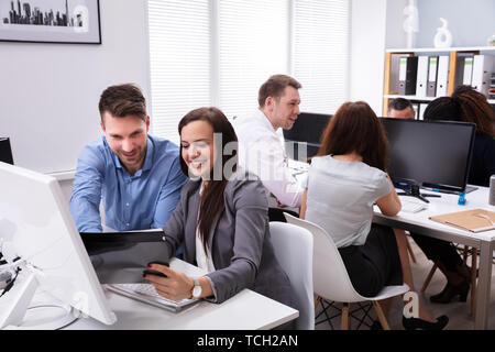 Portrait Of A Young Smiling Businesspeople Discussing On Document While Working In Office Stock Photo