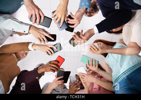 Group Of People Standing In Circle Using Smartphone Stock Photo