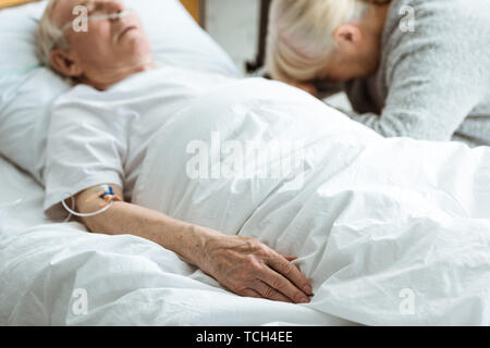 selective focus of sad senior woman with husband in coma in clinic Stock Photo