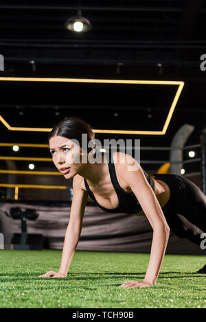 low angle view of athletic woman doing press ups on green grass Stock Photo