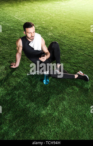 overhead view of handsome man using smartphone while sitting on grass Stock Photo