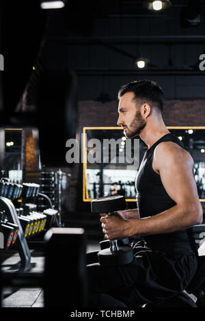 handsome athletic man working out with dumbbells in gym Stock Photo