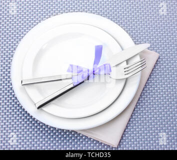 White empty plates with fork and knife tied with a ribbon on a grey tablecloth Stock Photo