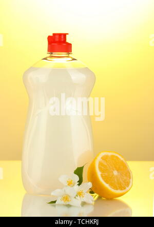 Dishwashing liquid, lemon and flowers on yellow background Stock Photo