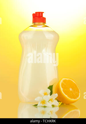 Dishwashing liquid, lemon and flowers on yellow background Stock Photo