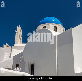 Worker repainting traditional cave house on Santorini Stock Photo