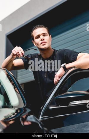 Successful arab man wear in striped shirt and sunglasses sitting on the  roof of his white suv car. 10515597 Stock Photo at Vecteezy