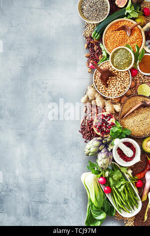 Food border with a large assortment of fresh fruit, spice, herbs and vegetables over a textured slate background with copy space Stock Photo
