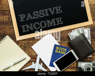 passive income, financial concept. text PASSIVE INCOME on chalkboard at the wooden table with book bank , money wallet , banknote , mobile phone Stock Photo