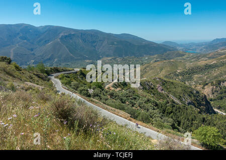 Road cyclist riding a bike on the beautiful road down from Cañar, Spain, with picturesque views of the Sierra Nevada and south to the coast Stock Photo