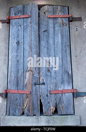 An old weathered wooden shutter is closed over a window Stock Photo