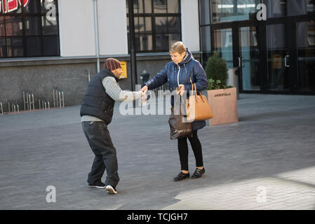 Kaunas, Lithuania, April 15, 2019: woman giving food to homeless beggar man in city Stock Photo