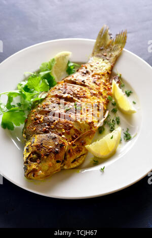 Grilled fish on plate over blue stone background. Stock Photo