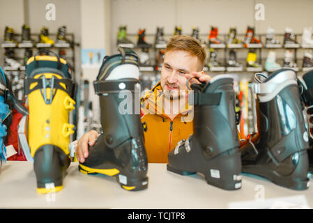 Male person choosing ski or snowboarding boots Stock Photo