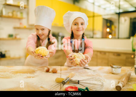 Two little girls cooks in caps shows dough balls Stock Photo