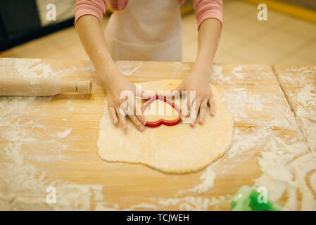 Little girl makes cookies in the shape of a heart Stock Photo