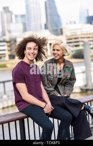 Happy couple talking sitting near River Thames. Stock Photo