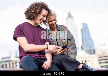 Happy couple talking sitting near River Thames. Stock Photo