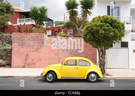 Yellow VW Beetle stands in front of red wall on the Canary Island La Palma, Spain Stock Photo