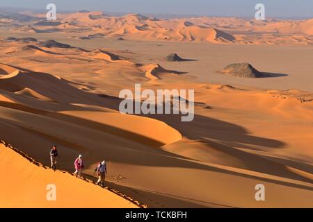 Group of people hiking in the sanddunes of Egedi In Djerane, Tassili NÂ´Ajjer National Park, Algeria, Sahara, Africa Stock Photo