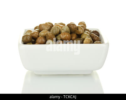 green capers in white bowl isolated on white background Stock Photo