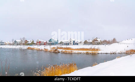 Panorama frame Panorama of a silvery lake with distant houses against cloudy sky in winter Stock Photo