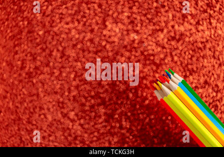 Colored pencils on glitter red background Stock Photo