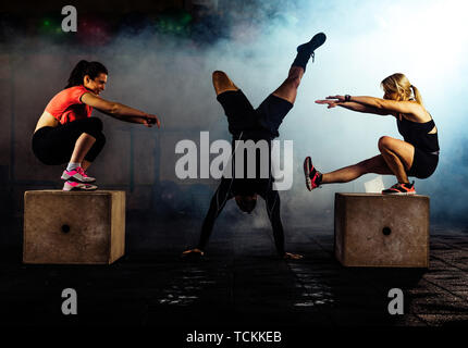 Trainer supervising muscular athletes doing jumping squats Stock Photo