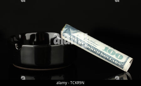 Cigar of the 100 dollar bill and an ashtray isolated on black Stock Photo