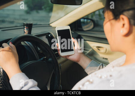 Mockup image of woman driver using smartphone with blank screen in a car. Stock Photo