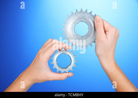 Man holding metallic cogwheels in his hands on blue background Stock Photo
