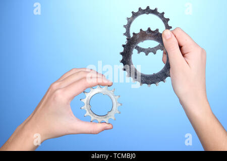 Man holding metallic cogwheels in his hands on blue background Stock Photo