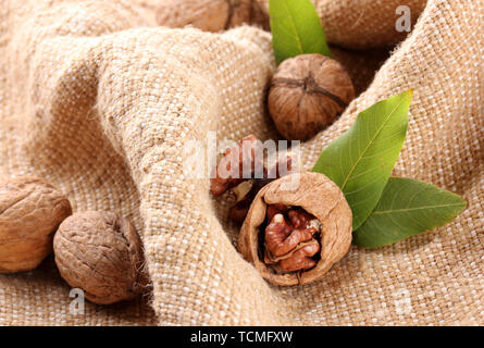 walnuts with green leaves, on burlap background Stock Photo