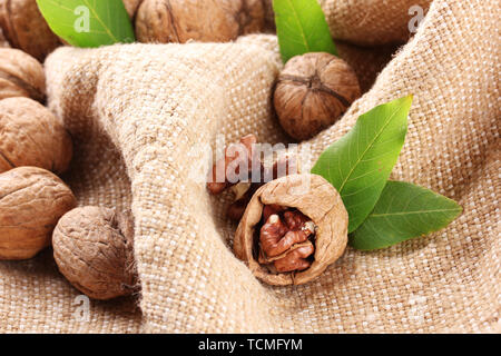 walnuts with green leaves, on burlap background Stock Photo