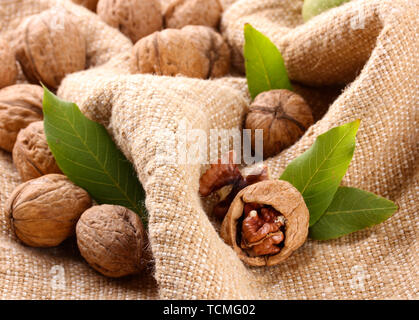 walnuts with green leaves, on burlap background Stock Photo